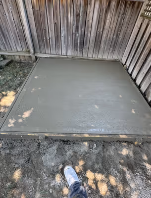 A close-up view of a construction site showing muddy ground and scattered building materials, possibly the foundation work.